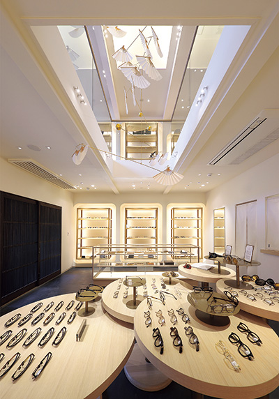 A modern interior with white as its base. In the central atrium, there is an object using a Kyoto fan. It expresses the brand's world view.