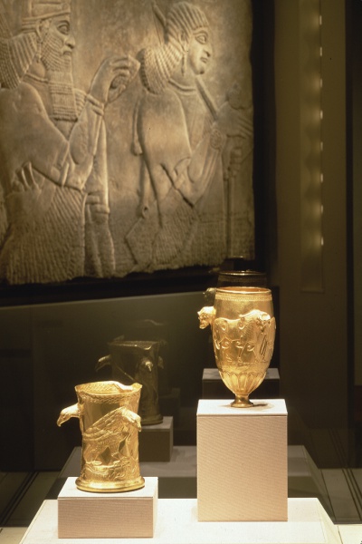 (bottom) raptor-decorated cup and bull-decorated leg cup; (top) relief of Assyrian relief of a spirit and attendant.