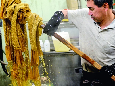 Dyeing by a traditional craftsman. The way the cloth is folded and the force with which the thread is wrapped around the cloth changes the appearance of the pattern.