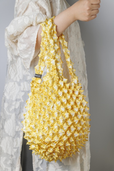 A unique button-shaped fabric bag. Its casual check pattern makes it easy to use.