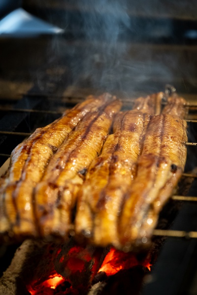 焼き場で職人が鰻を丹精に焼き上げる。タレ付けと焼きを4度重ねることで、香ばしさとうま味を引き出す。
