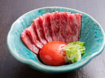 コースメニューの一品・近江牛炙りユッケ。近江牛のサーロインに濃厚な濃紅たまごの卵黄を絡めていただく。
