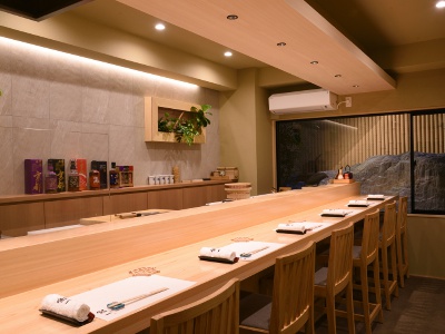 木のカウンターが温かみを感じさせる空間。中庭には四万十川の名石が置かれている。