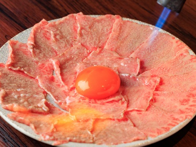 目の前で炙って仕上げるユッケ。じんわりと焼き色が付いていく様子に食欲がかき立てられる。