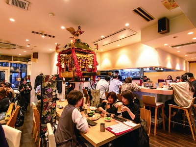 An open atmosphere with glass walls. There is a portable shrine in the shop and the open kitchen is full of life.