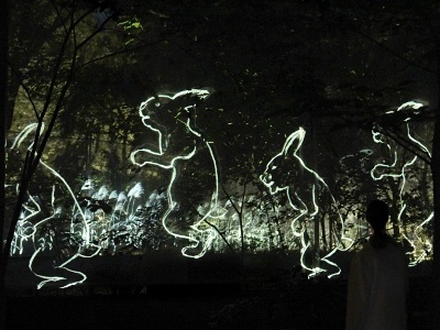 In “Walk, Walk, Walk - Secondary Forest,” a computer program continuously paints diverse portraits of people and animals in real time, which float in the forest.